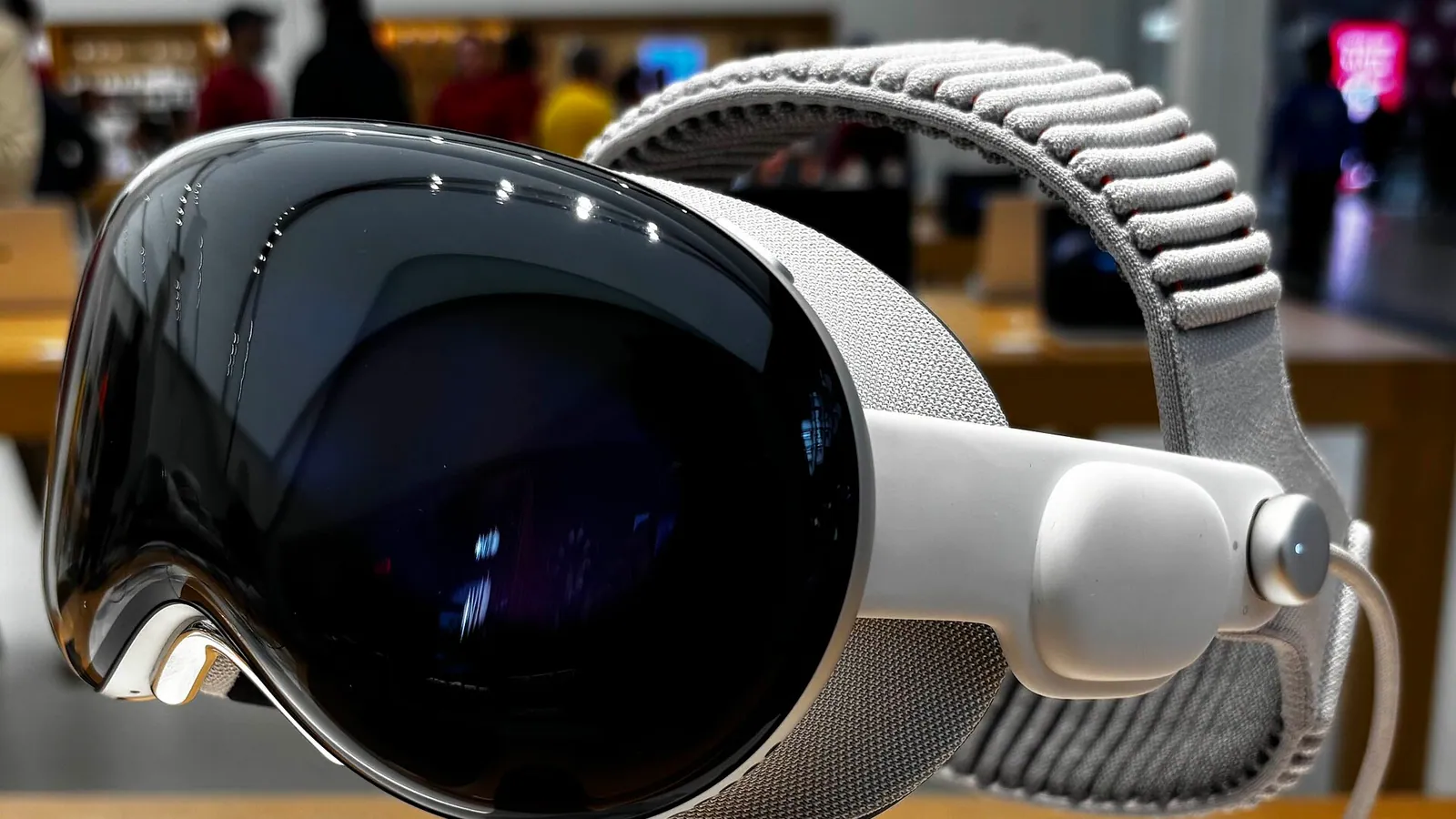 A professional wearing an Apple Vision Pro headset interacting with floating 3D data panels in an office