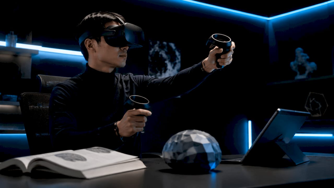 Hands holding VR controllers over neuroscience study materials