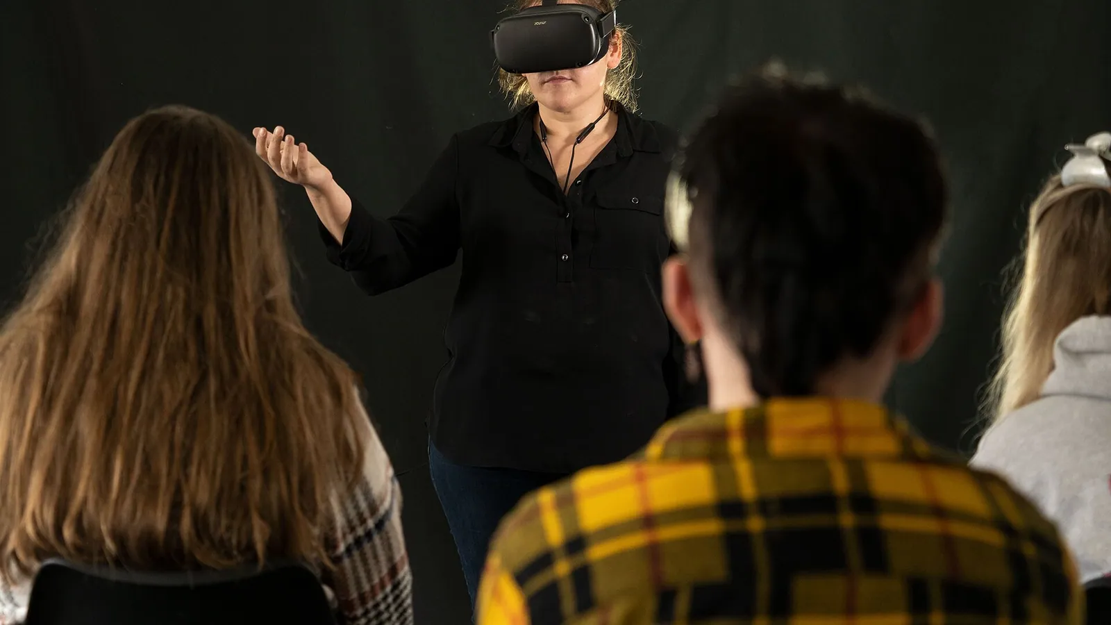 An employee in a VR headset doing an onboarding simulation beside a laptop showing an e-learning module